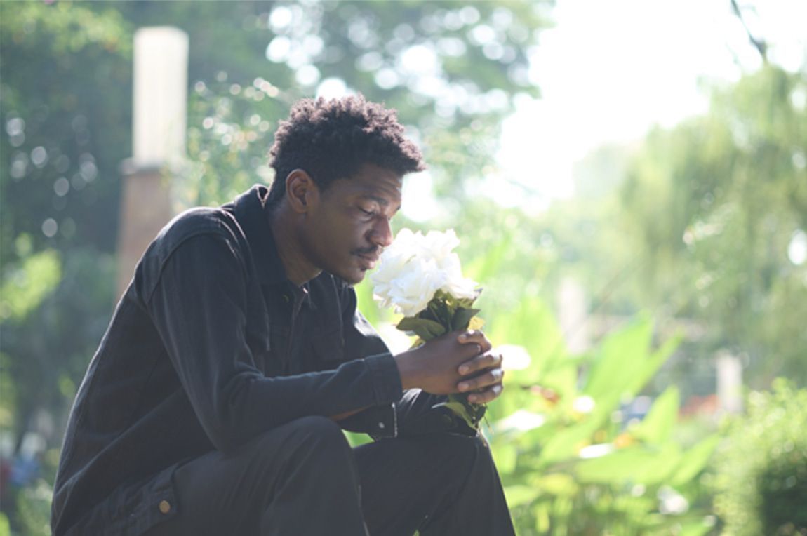 Man holding white flowers while grieving