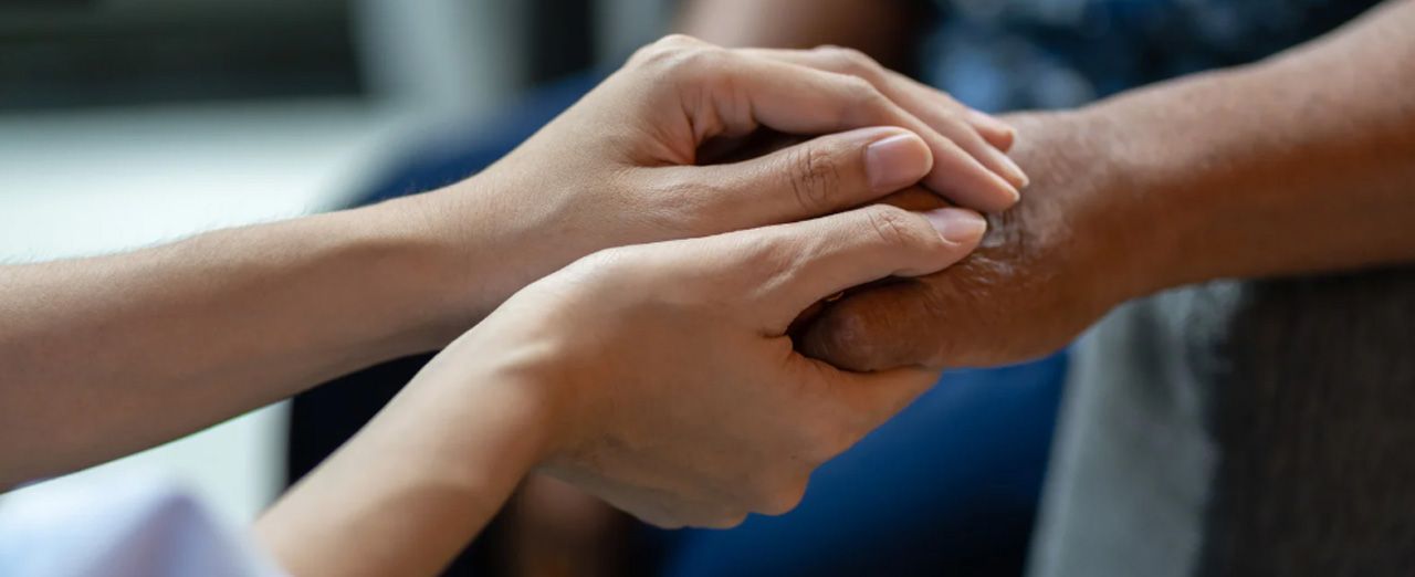 Person holding another person's hand for comfort
